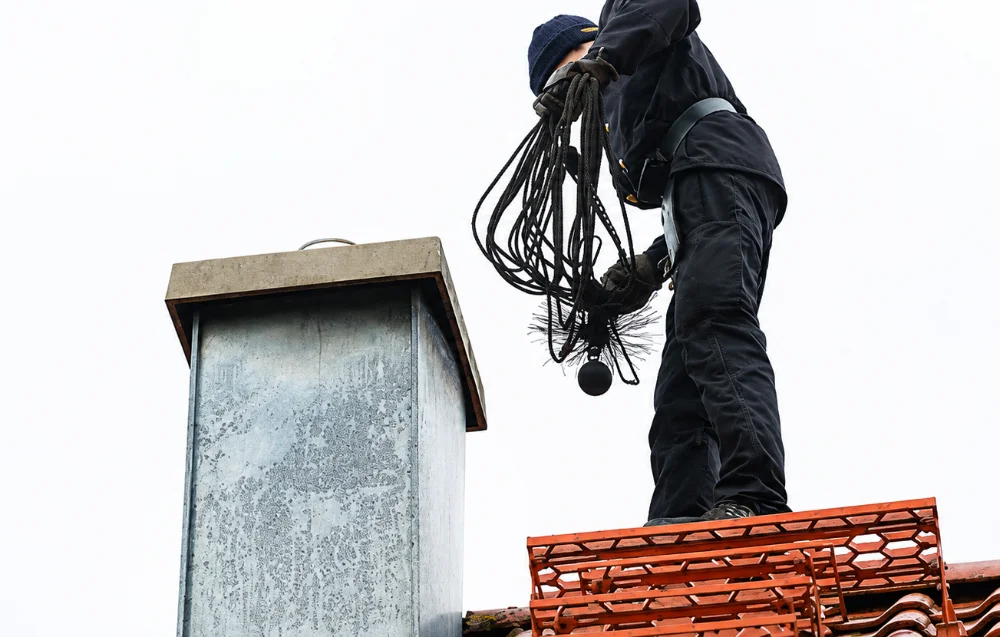 Ramoneur avec son hérisson et ses cordages près d’un conduit de cheminée